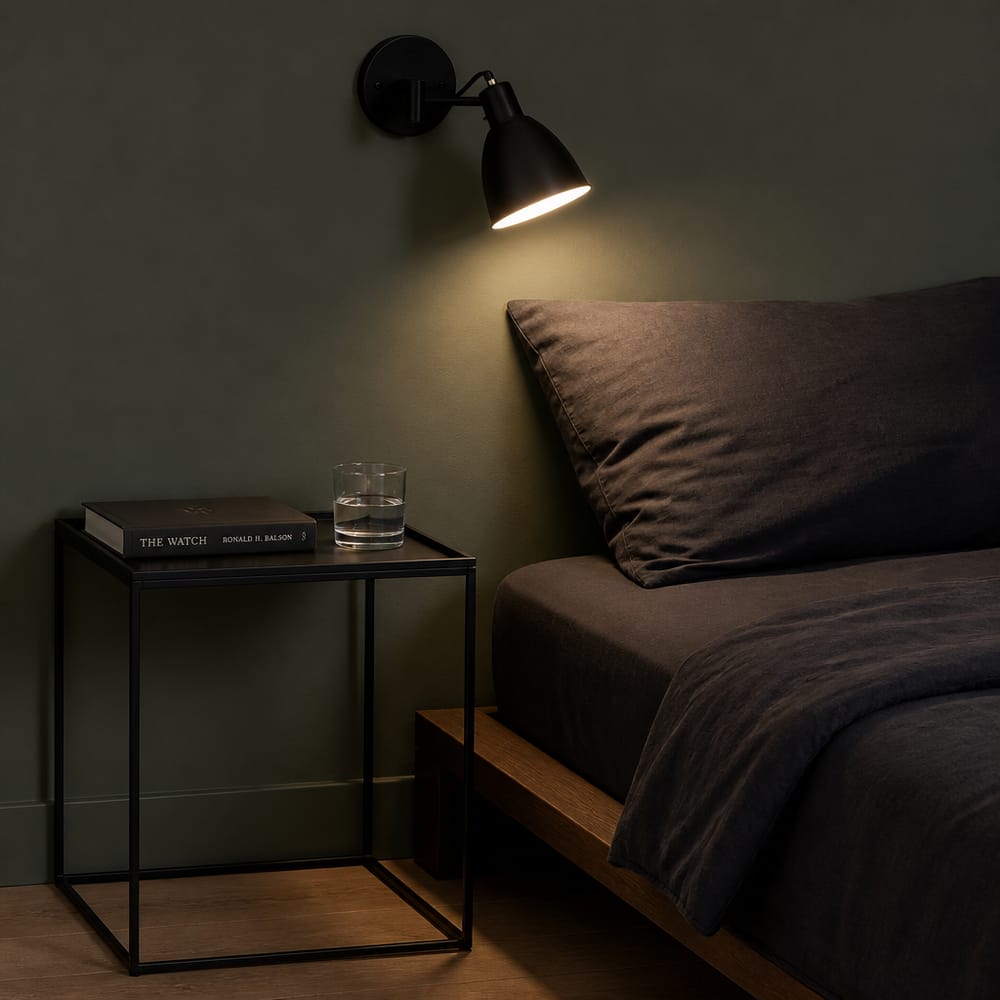 Mesita delgada junto a la cama, lámpara de lectura en la pared apuntando abajo