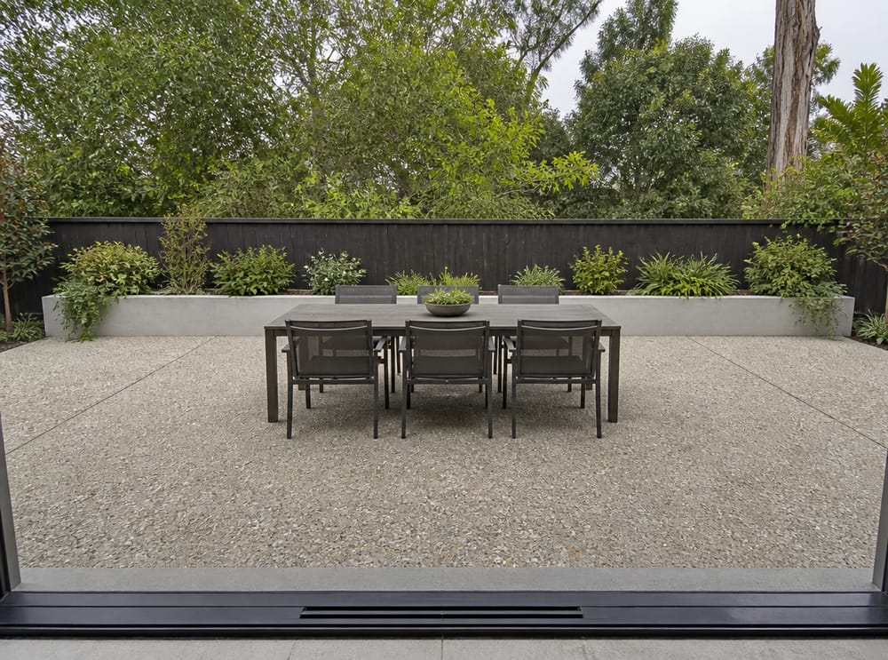 Patio comedor de árido expuesto con jardinera de concreto