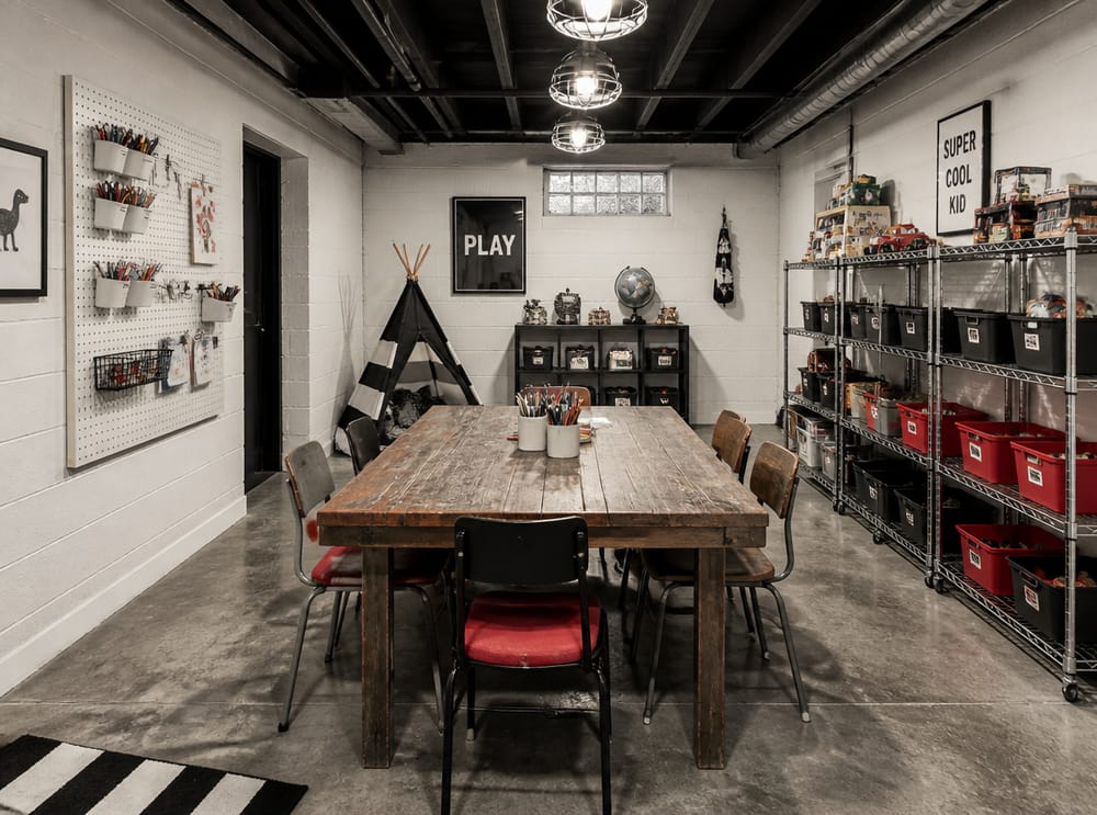 Sala de juegos estilo industrial con muros de bloque de concreto y mesa de granja