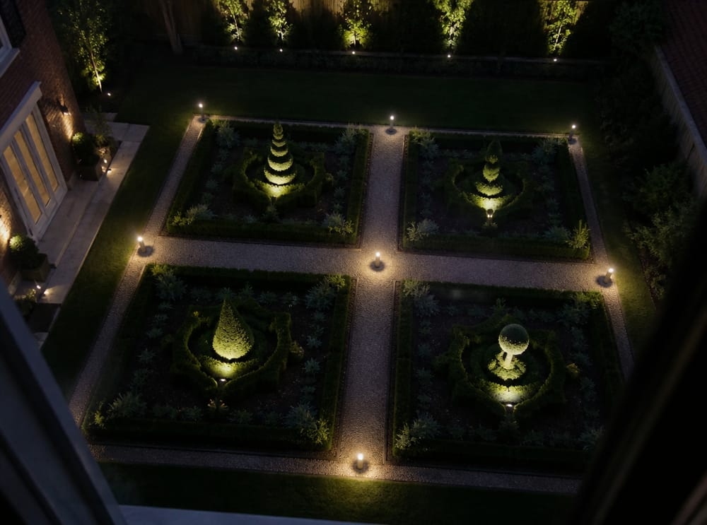 Formal garden quadrants lit with topiary accent spotlights