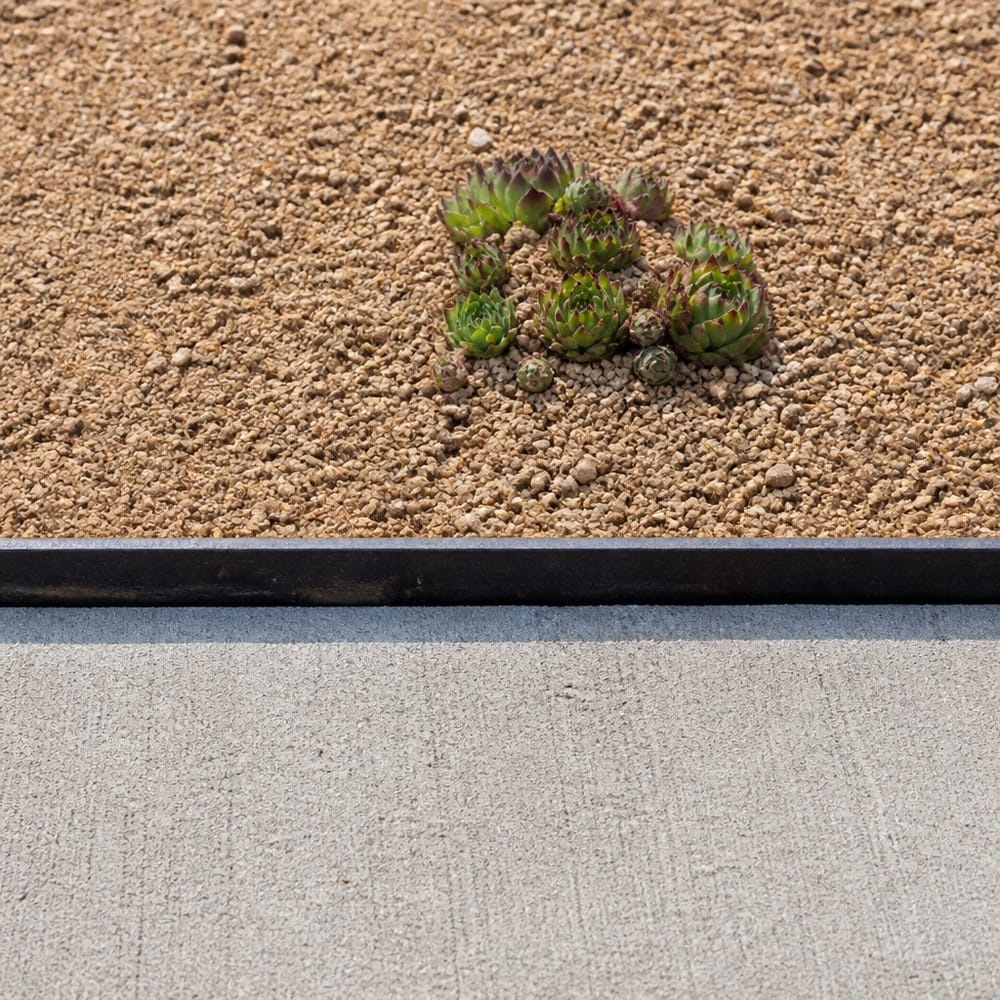 Steel edging detail between sidewalk and gravel bed