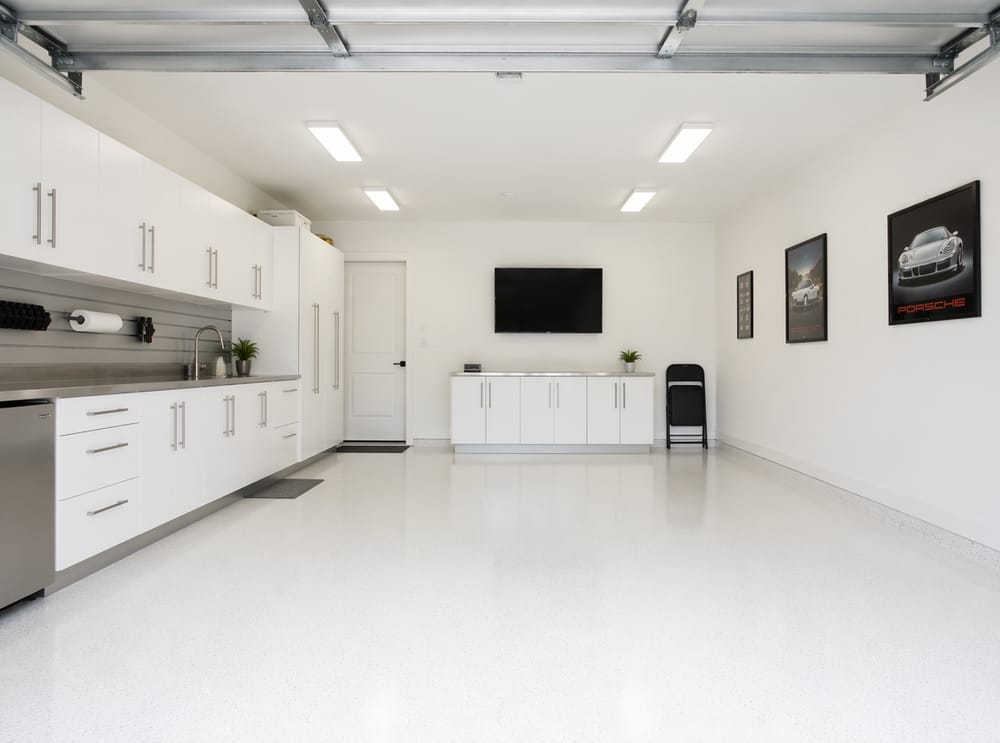 Garaje totalmente blanco con encimera de acero inoxidable y TV en la pared