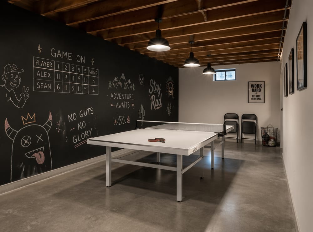 Pared de pizarrón junto a mesa de ping-pong, techo con vigas expuestas