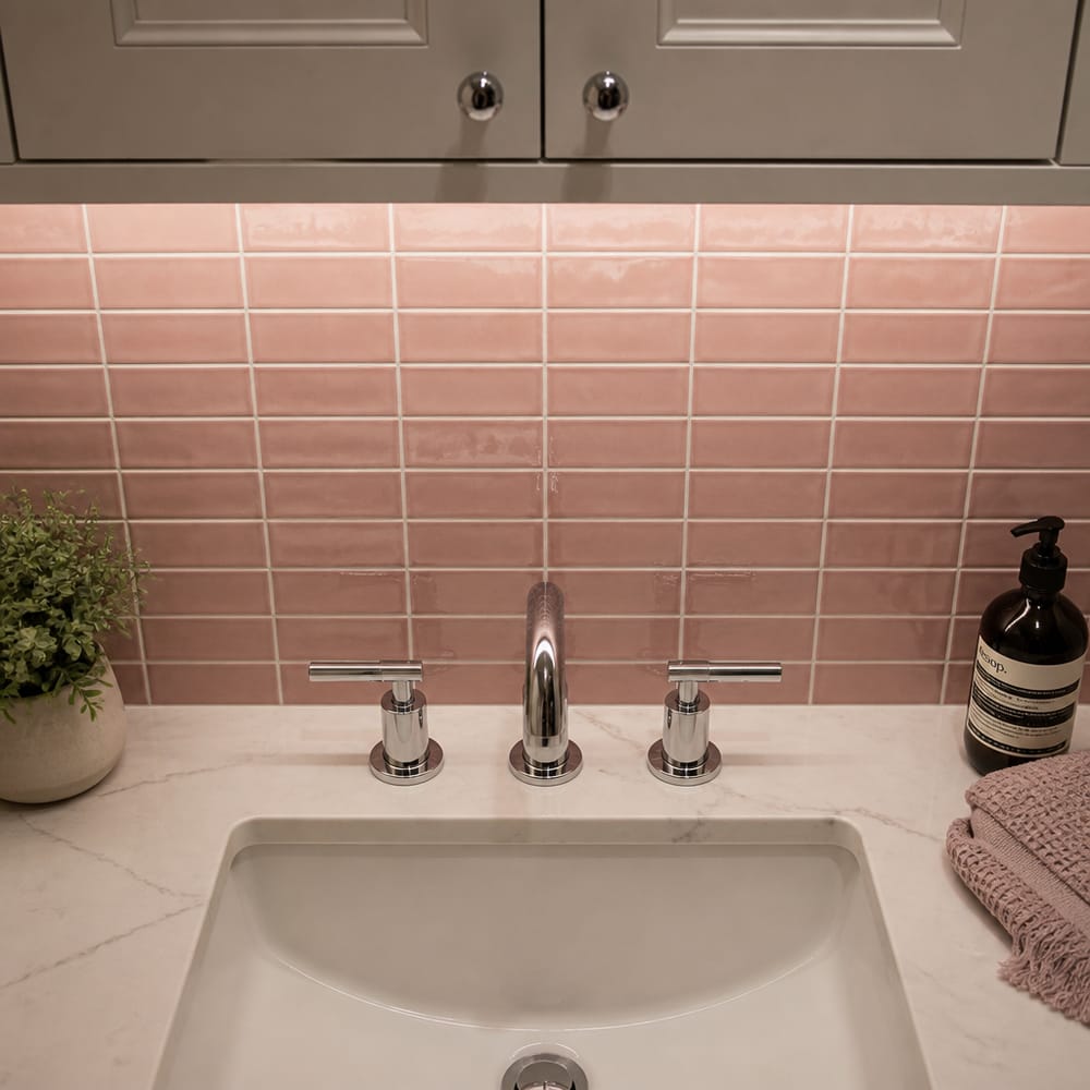 Dusty rose glossy backsplash tile behind vanity basin