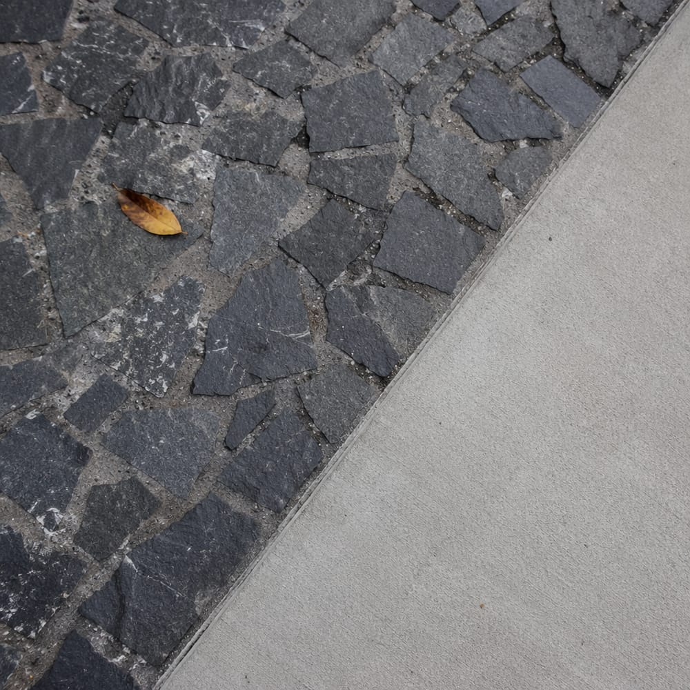 Dettaglio mosaico in basalto con bordo in cemento
