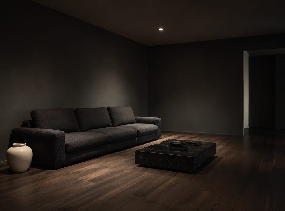 Sofá bouclé antracita en sala minimalista de tonos oscuros